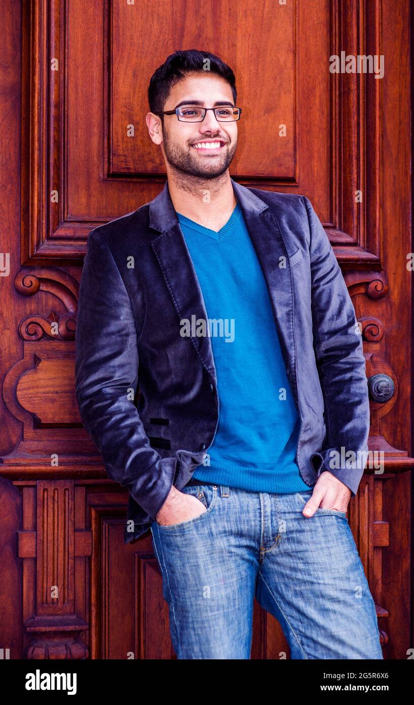 Portrait de jeune boursier. Un jeune homme, portant un blazer bleu foncé en  laine, un Jean bleu, un chandail bleu, des lunettes, et deux mains mettant  dans les poches Photo Stock -