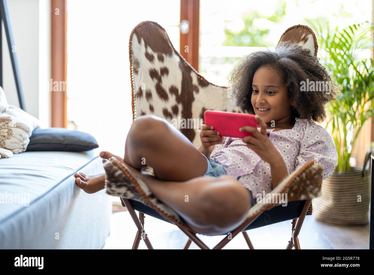 Fille jouant à des jeux sur téléphone portable à la maison Banque D'Images