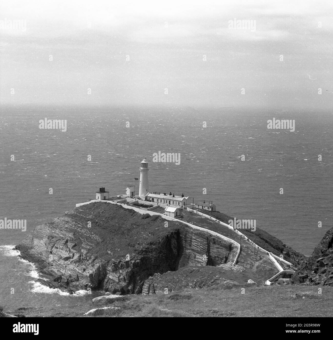 1966, vue aérienne historique sur le phare de South Stack et les bâtiments de soutien de Holy Island, Anglesey, pays de Galles, Royaume-Uni. Situé sur la roche périphérique sur une petite île au large de la côte nord-ouest de l'île Sainte, il a été construit en 1809 par Trinity House pour avertir les navires des roches dangereuses environnantes. Banque D'Images