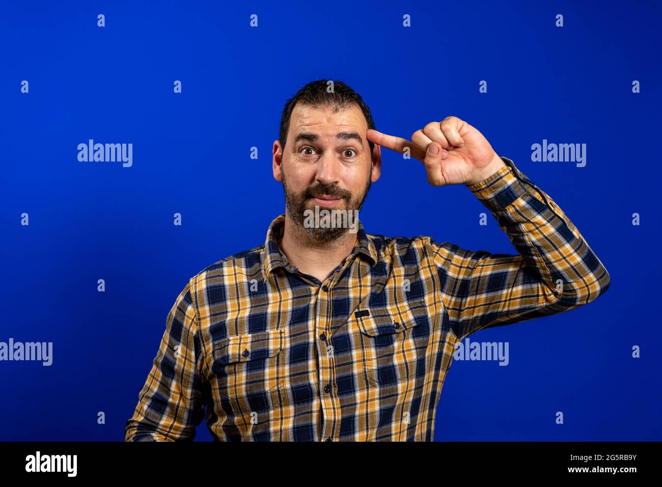 Beau homme d'âge moyen sur fond bleu isolé souriant pointant vers la tête avec un doigt, grande idée ou pensée, bonne mémoire. Banque D'Images