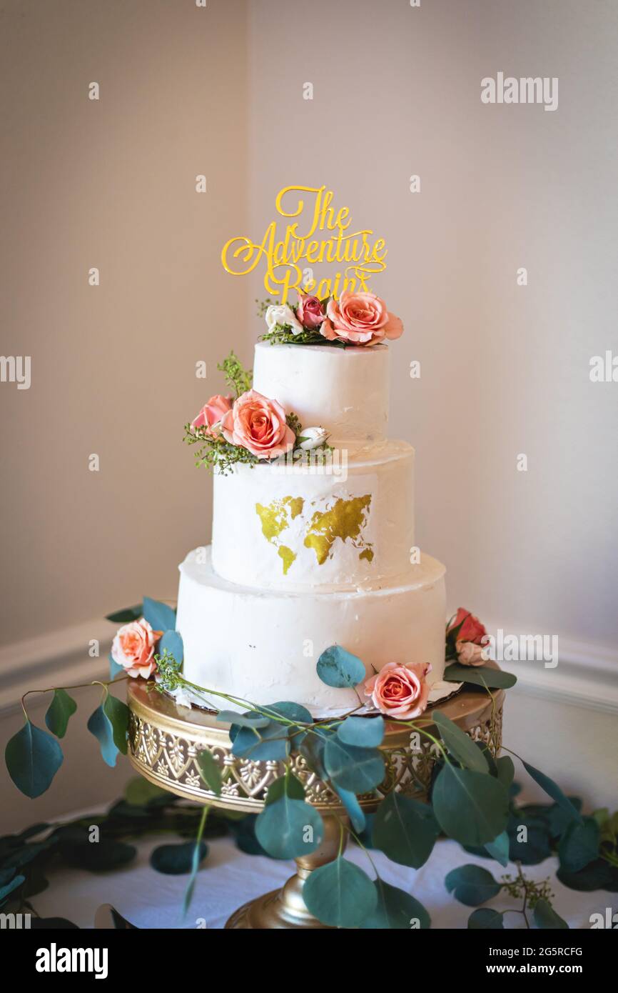 Magnifique gâteau de mariage sur le thème du voyage personnalisé avec carte du monde comestible, roses roses, et message The Adventure commence Banque D'Images