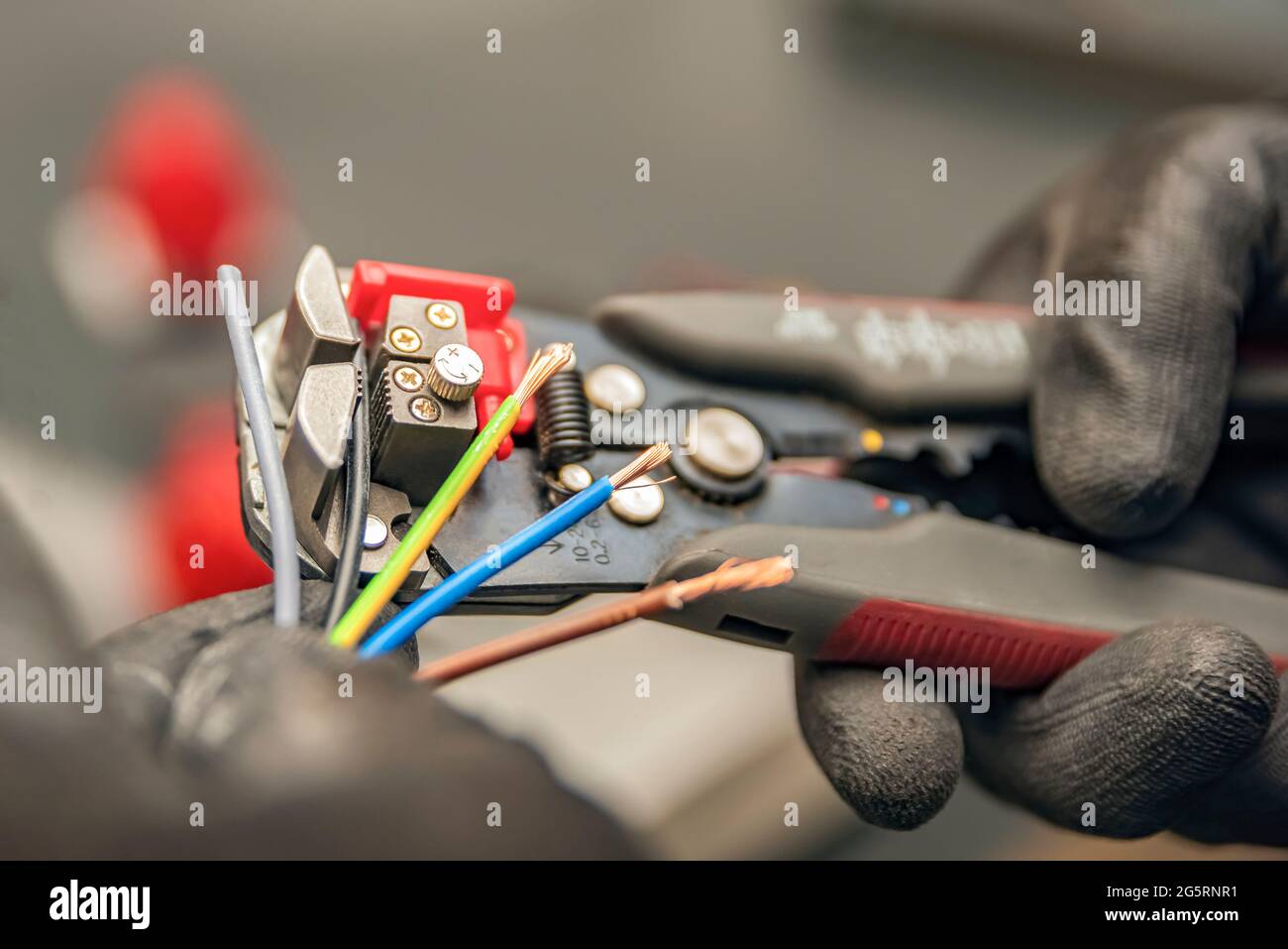 Pinces à dénuder. L'électricien nettoie l'isolation de protection du fil à l'aide d'une pince à dénuder. Le processus de connexion des fils. Gros plan Banque D'Images