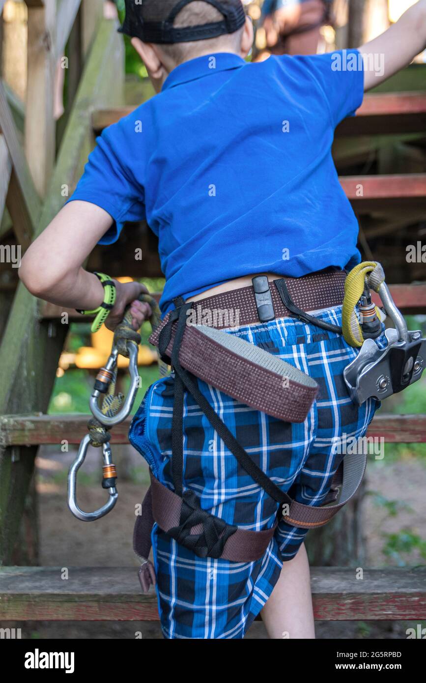 Parc d'attractions Forest Adventure. Un enfant avec un équipement spécial surmonte les obstacles dans le parc d'aventure forestier. Bannière pour la publicité et place à insérer Banque D'Images