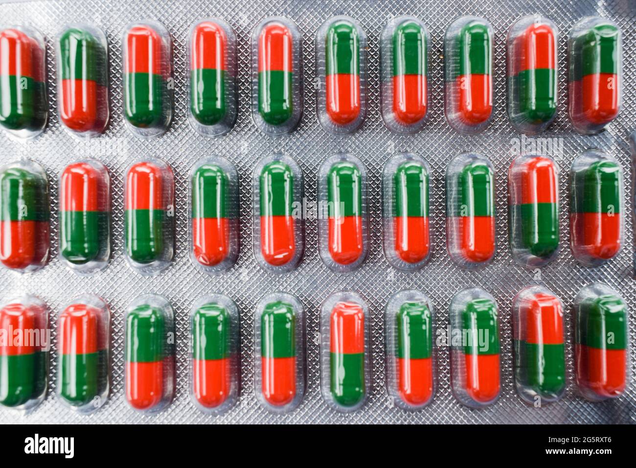 Capsules de couleur rouge et verte arrière-plan. Texture des comprimés ayurvédiques pour le soulagement des symptômes sinusaux. Banque D'Images