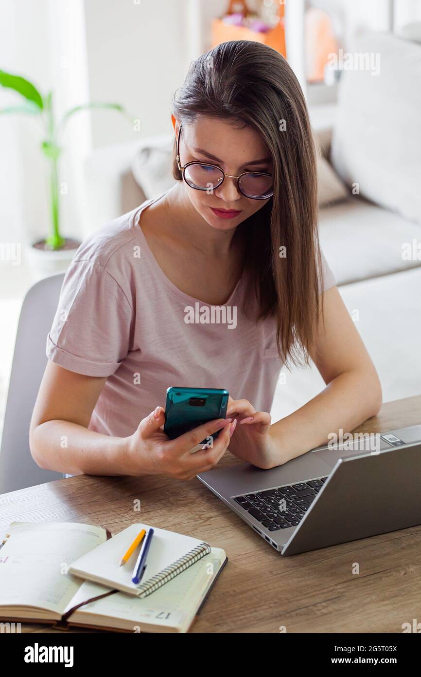 Jeune femme utilisant un téléphone mobile et un ordinateur portable pour travailler à la maison, le travail à distance Banque D'Images