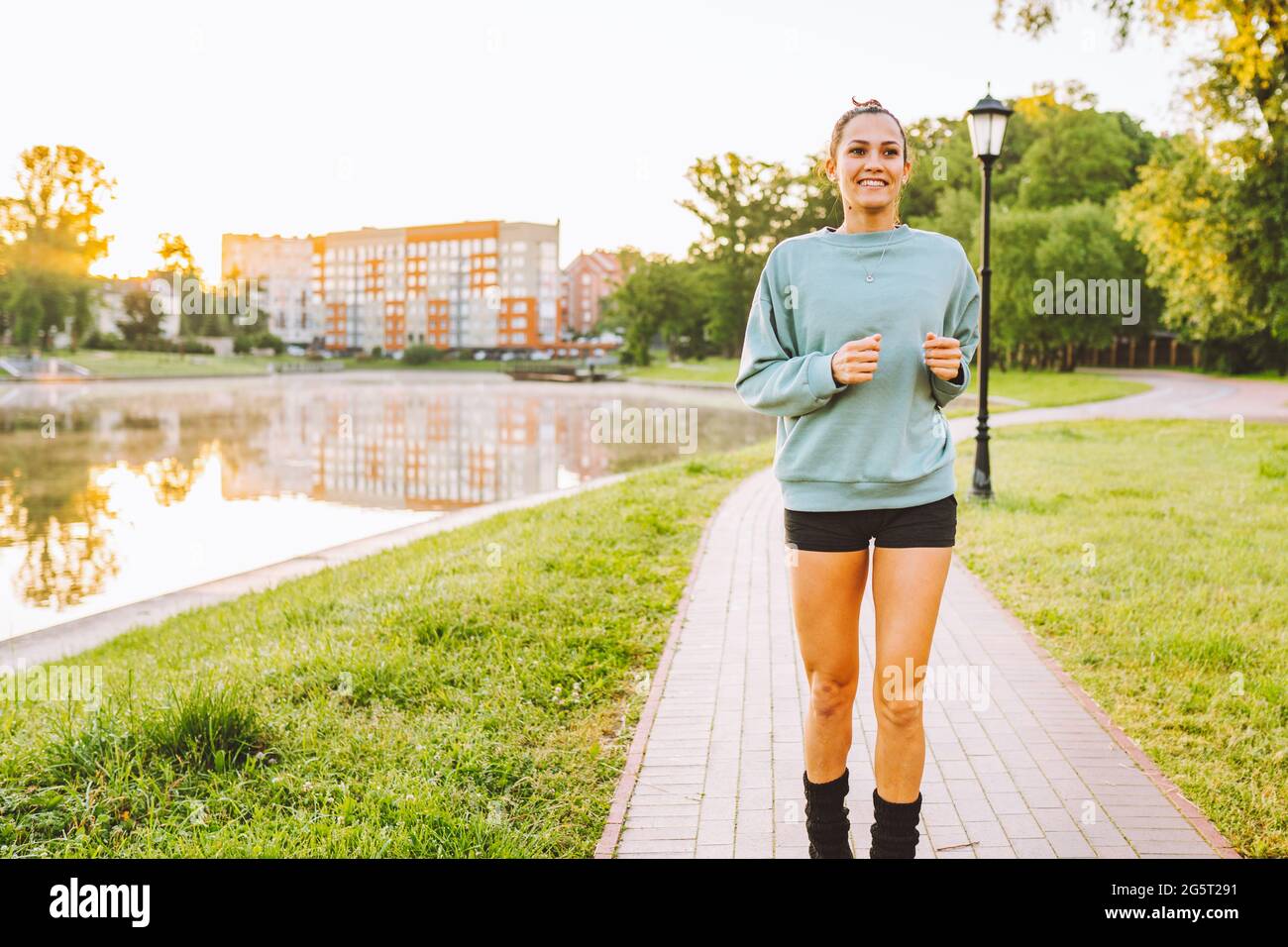 Jeune femme sportive portant des vêtements de sport courant dans le parc public le matin Banque D'Images
