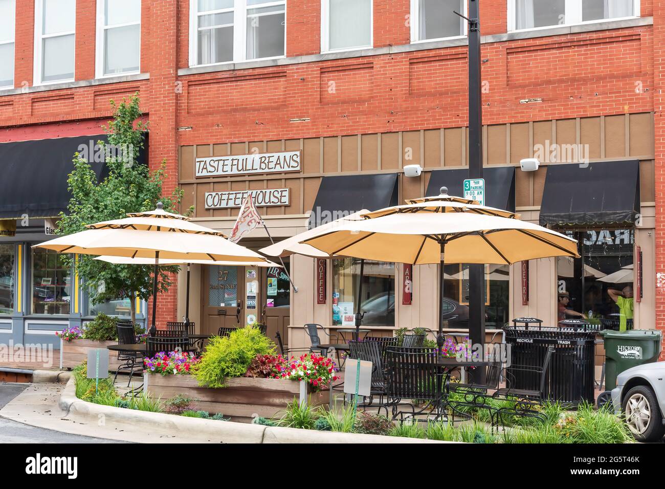 HICKORY, NC, USA-22 JUIN 2021: Vue diagonale avant de Taste Full Beans Coffeehouse, avec des fleurs colorées et de la verdure entourant les tables de trottoir. Banque D'Images