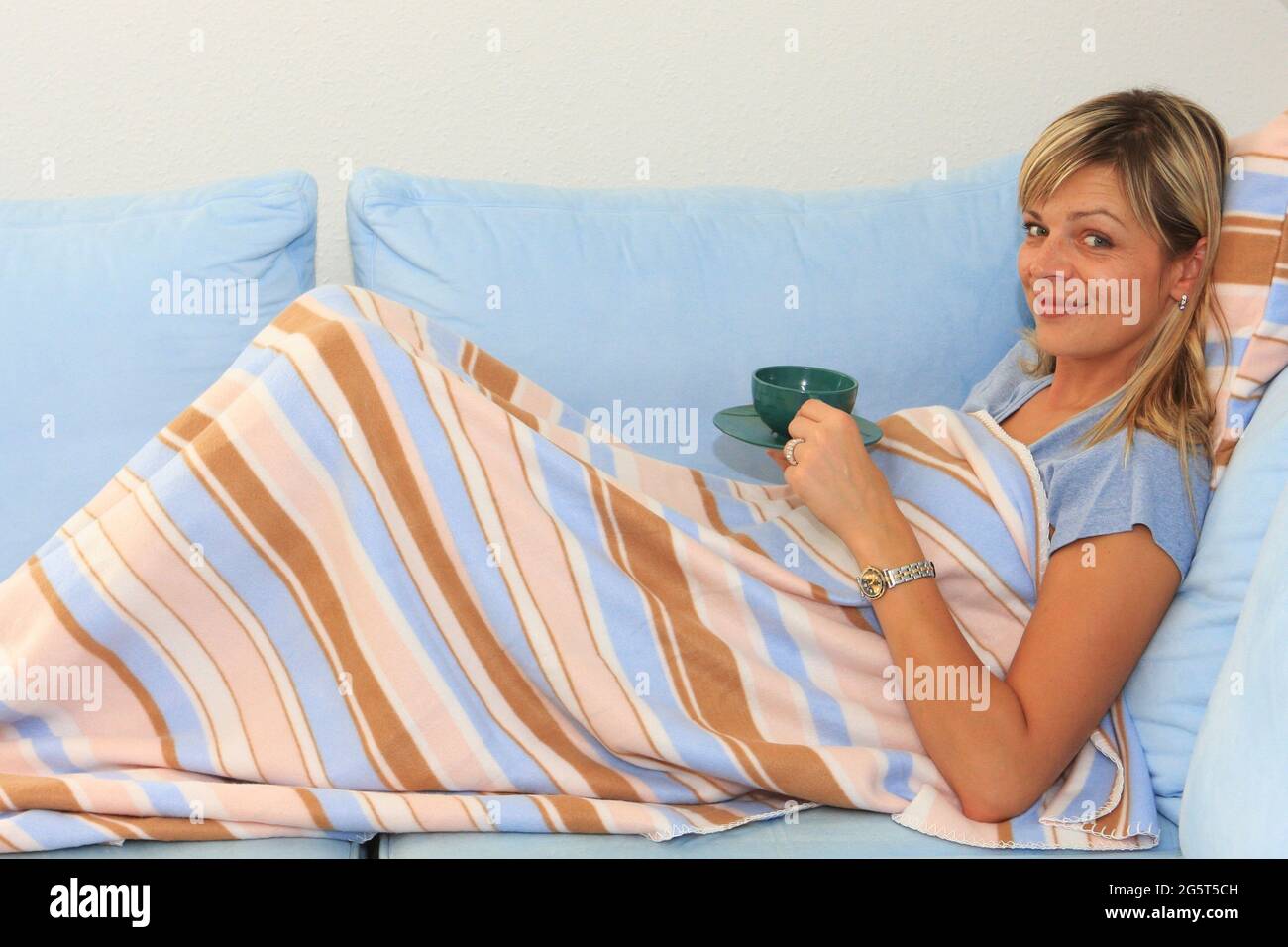 une femme boit du thé sur un canapé Banque D'Images