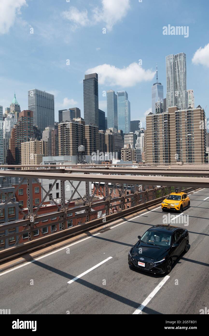 Un taxi et une voiture traversant le pont de Brooklyn vu d'en haut. Les gratte-ciel de New York sont visibles en arrière-plan. Banque D'Images