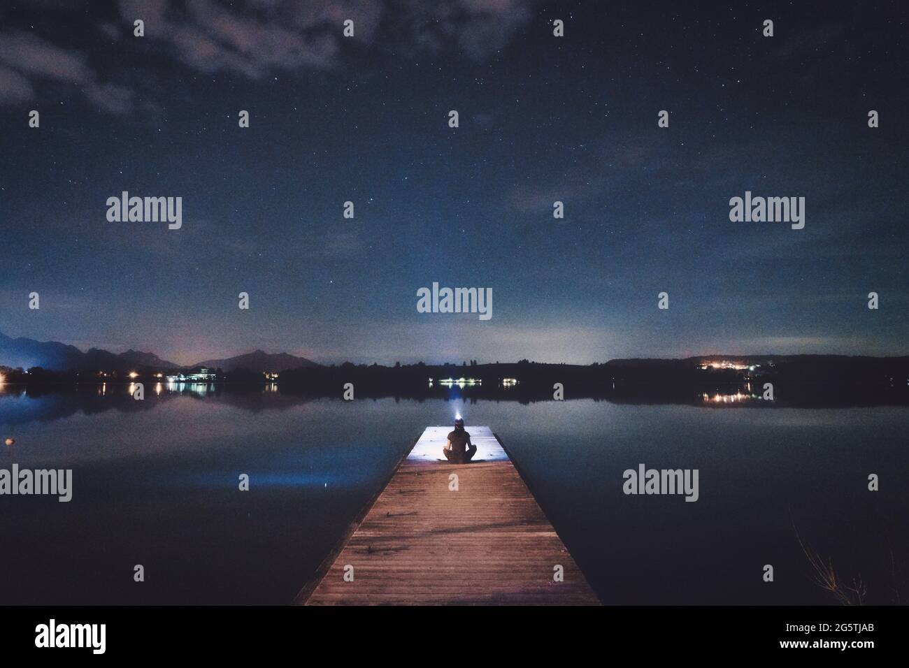 Une jetée en bois menant dans un plan d'eau dans le ciel nocturne, Forggensee, Allemagne Banque D'Images