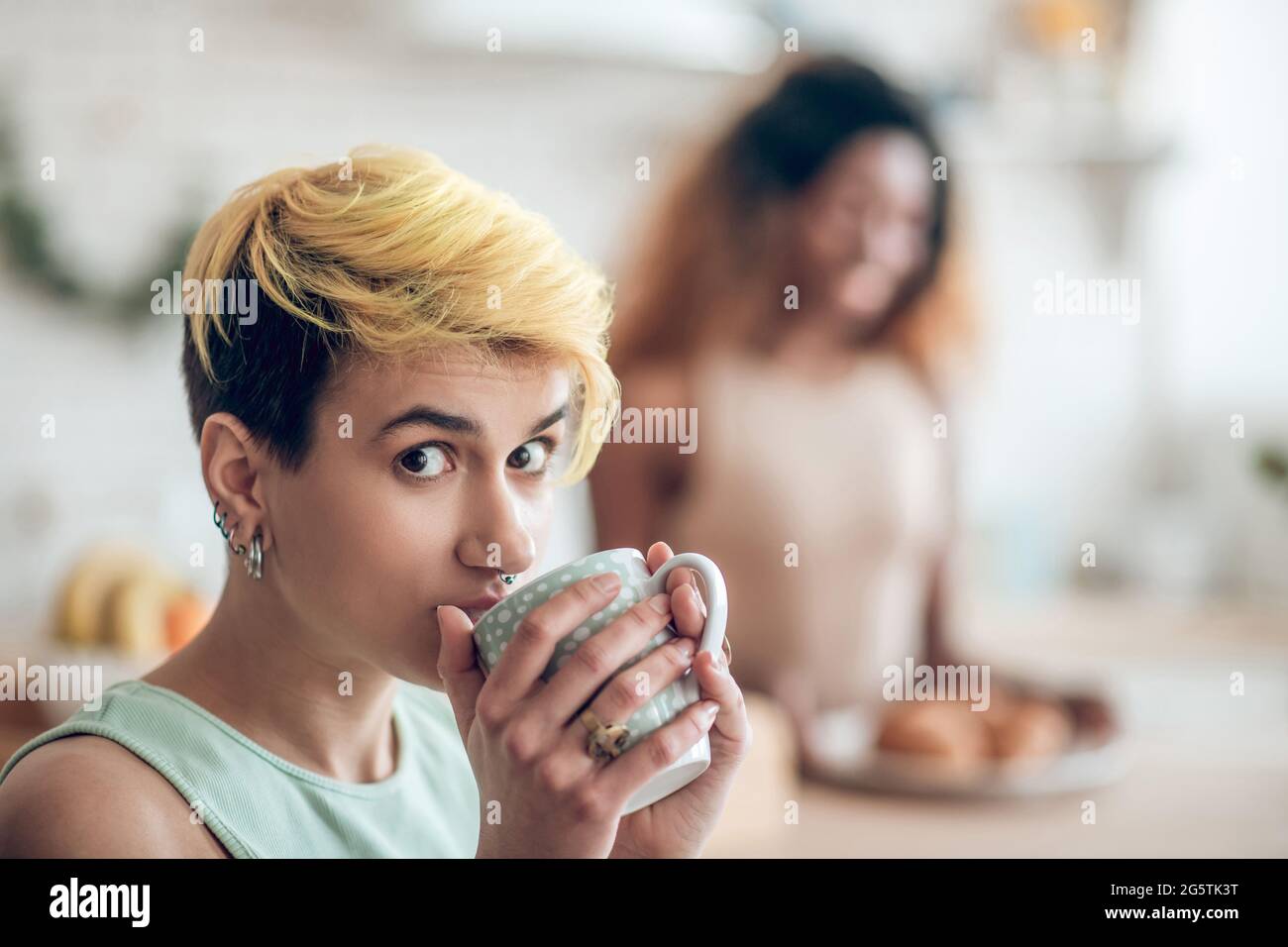 Visage de jeune femme regardant avec intérêt avec la tasse Banque D'Images