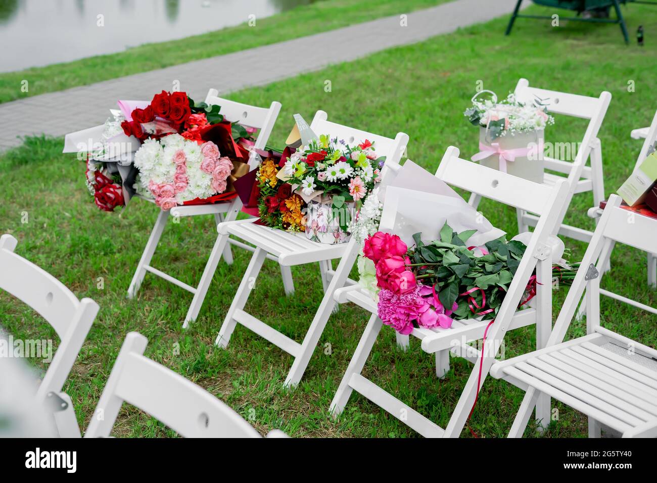 bouquets de fleurs sur des chaises blanches en bois lors de la cérémonie de sortie. Banque D'Images
