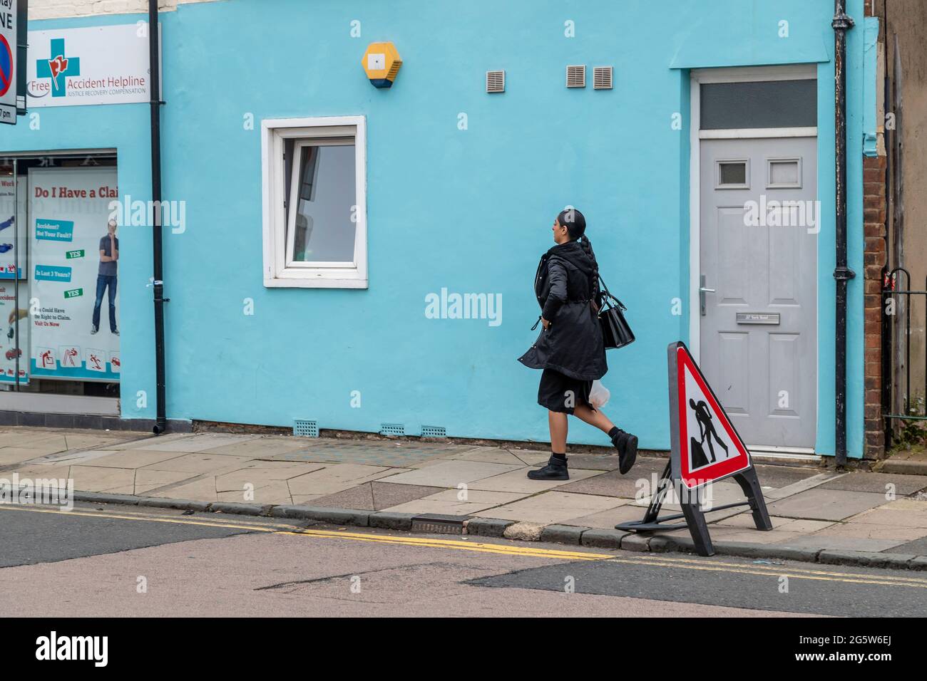 Femme portant un masque facial en marchant de droite à gauche dans la rue de St Edmund Northampton, Engalnd, Royaume-Uni Banque D'Images