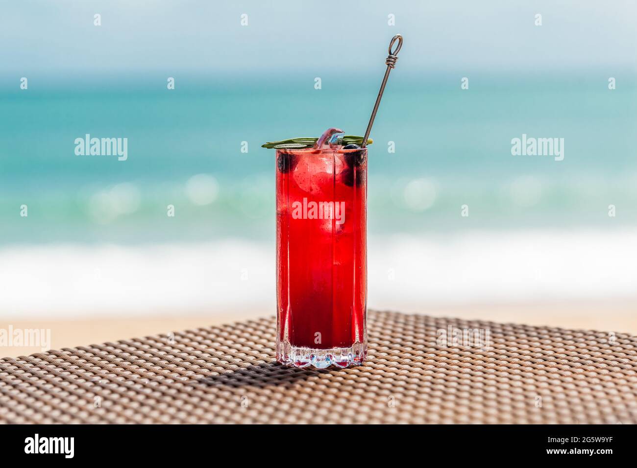Cocktail de baies rouges fraîches sur la table de plage, mer turquoise défoqué sur fond Banque D'Images