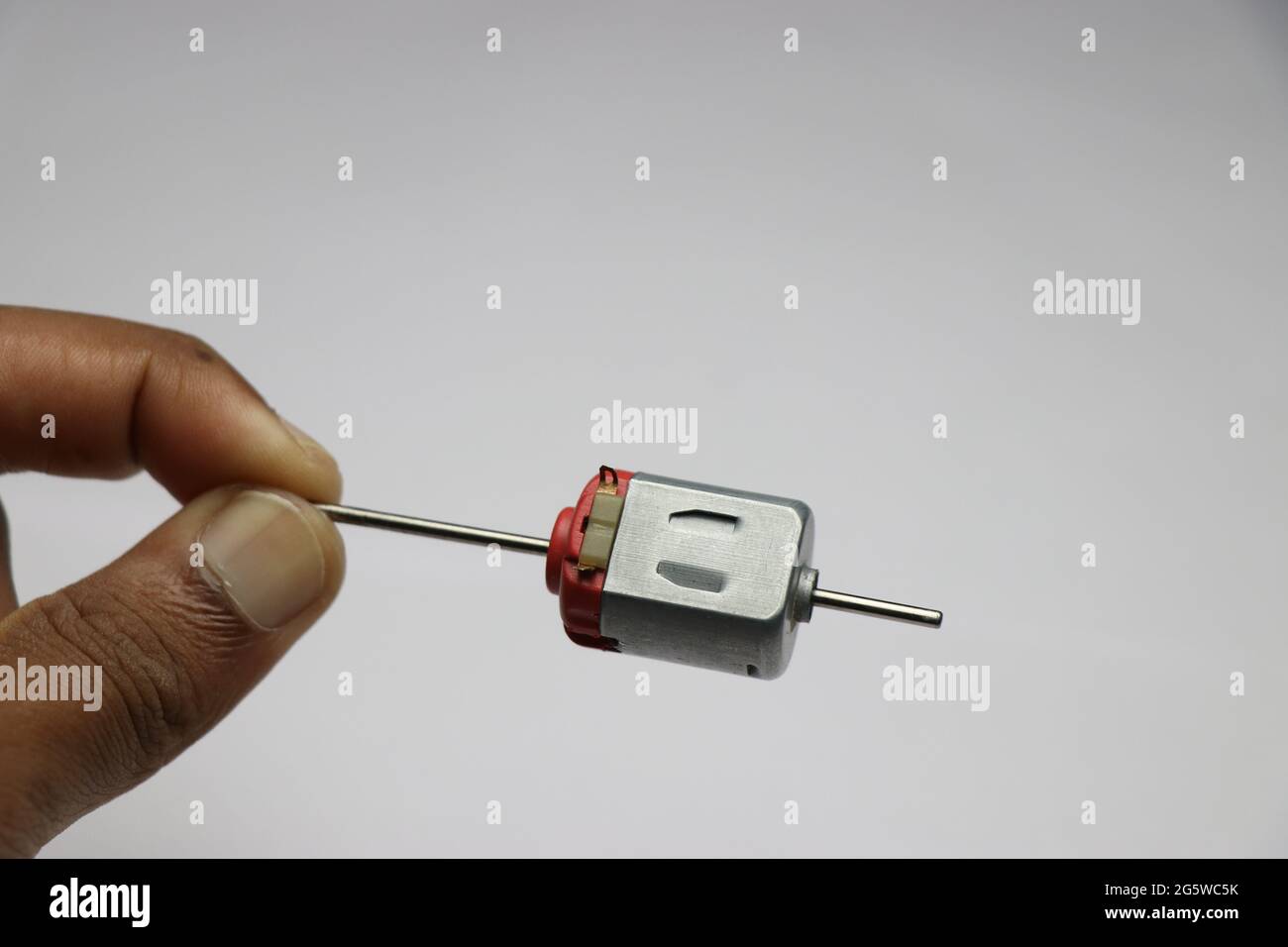 Maintenir à la main une extrémité de l'arbre du moteur cc à double arbre. Moteur DC pour l'électronique de loisir et les petits projets d'invention Banque D'Images