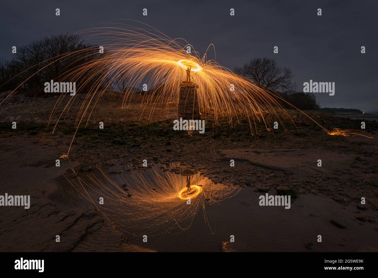 Un halo de feux d'artifice et d'étincelles au-dessus d'une personne se tenait sur un mur au-dessus d'une plage Banque D'Images