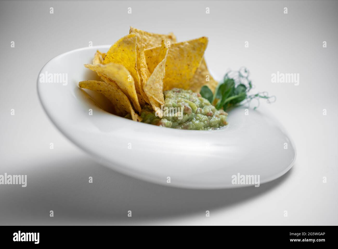 gros plan de la sauce guacamole dans un bol avec avocat et nachos sur fond blanc Banque D'Images