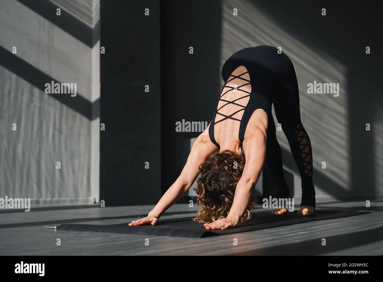 Une jeune femme pratiquant le yoga pose dans un fond urbain par temps ensoleillé Banque D'Images