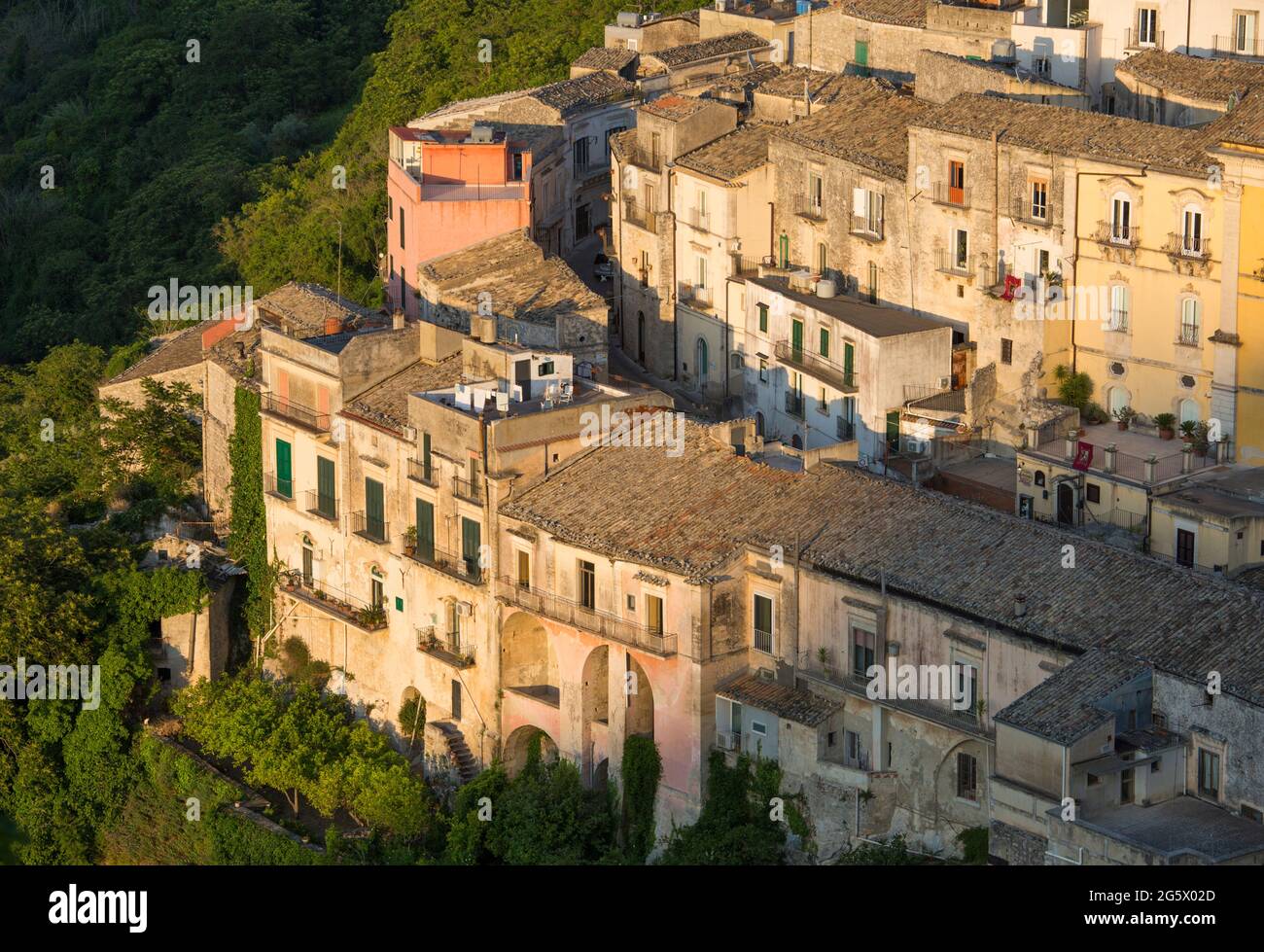 Ragusa, Sicile, Italie. Vue sur les toits pittoresques de Ragusa Ibla, coucher de soleil, maisons accrochée à la colline abrupte au-dessus de gorges boisées. Banque D'Images