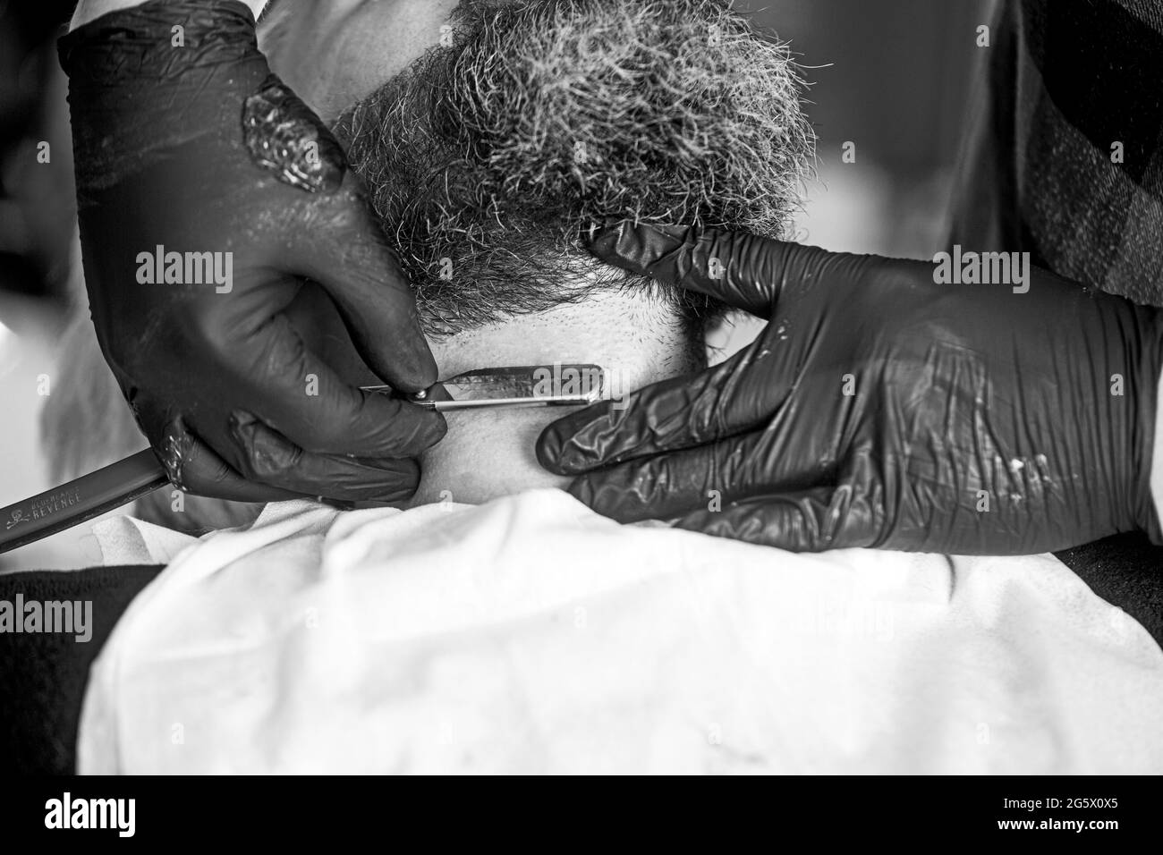 Vue rapprochée d'un jeune homme barbu qui obtient une coupe de barbe en coiffeur au salon de coiffure. Une forme parfaite. Banque D'Images