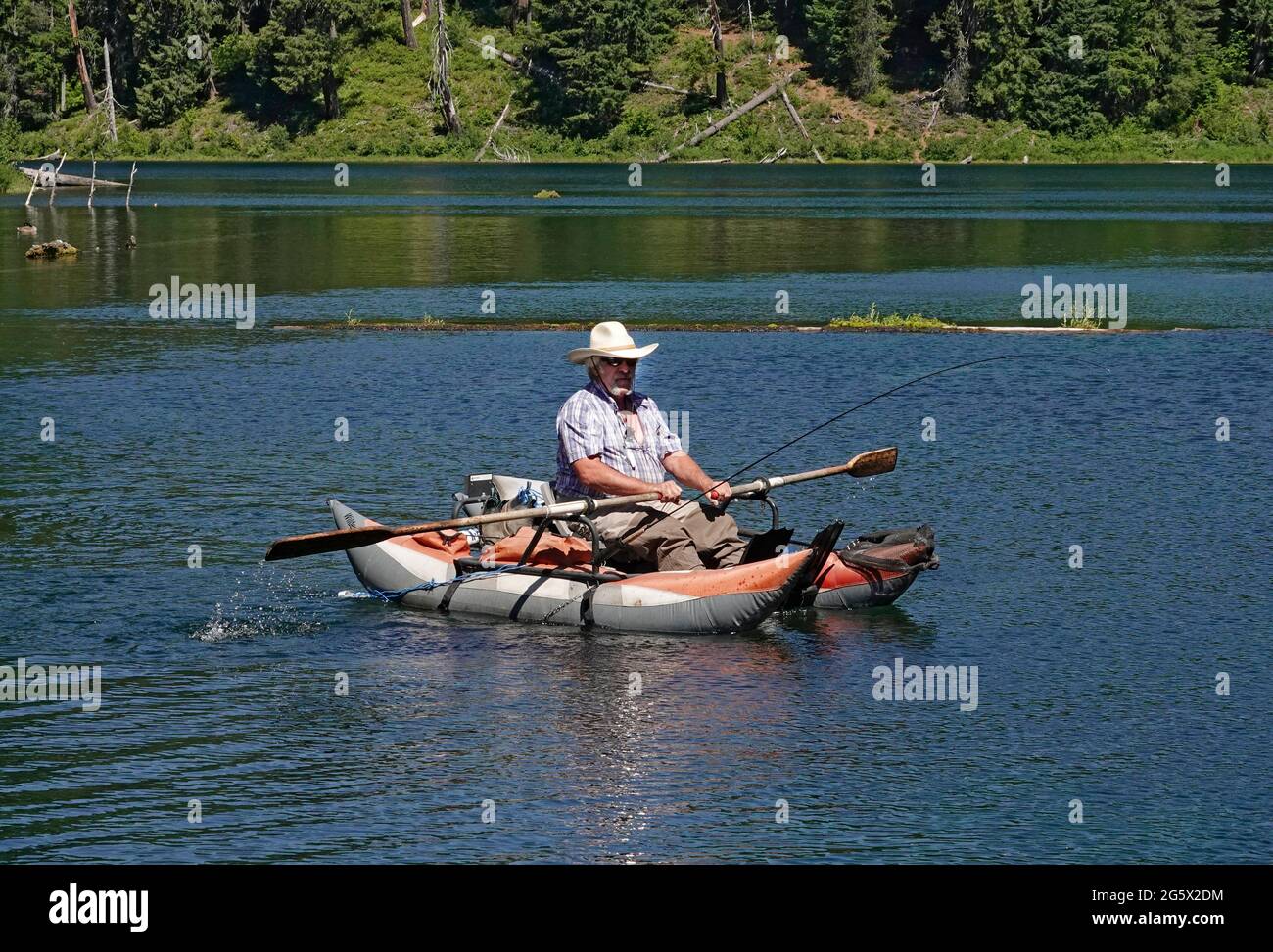 Un pêcheur d'âge moyen se rafraîchit dans un radeau de caoutchouc sur Clear Lake lors d'une chaude journée d'été dans les Cascades de l'Oregon. Banque D'Images