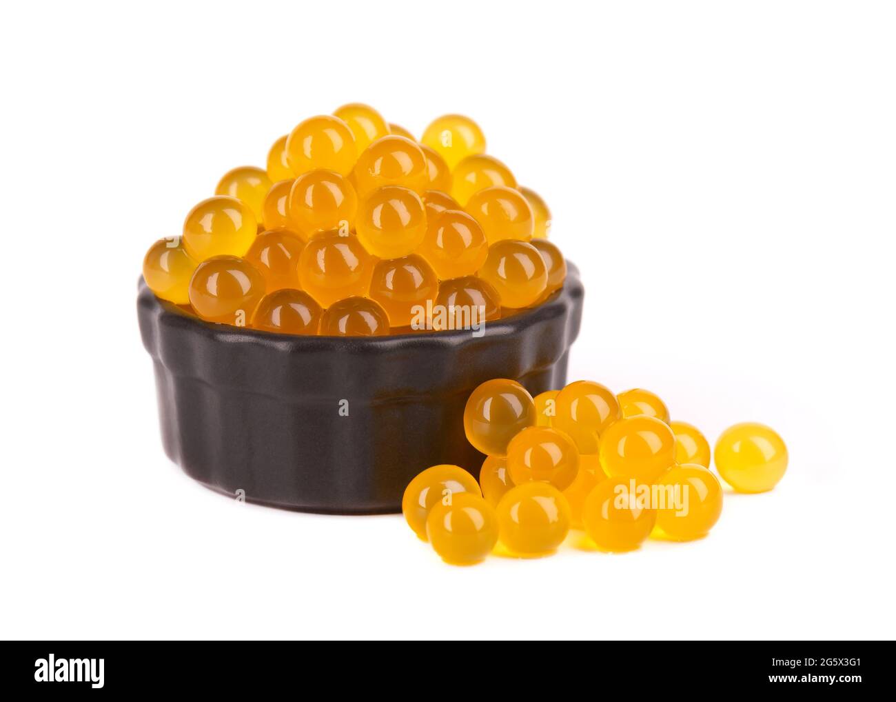 Perles de tapioca jaune pour le thé à bulles isolées sur fond blanc. Perles de tapioca dans un bol en céramique noire. Banque D'Images