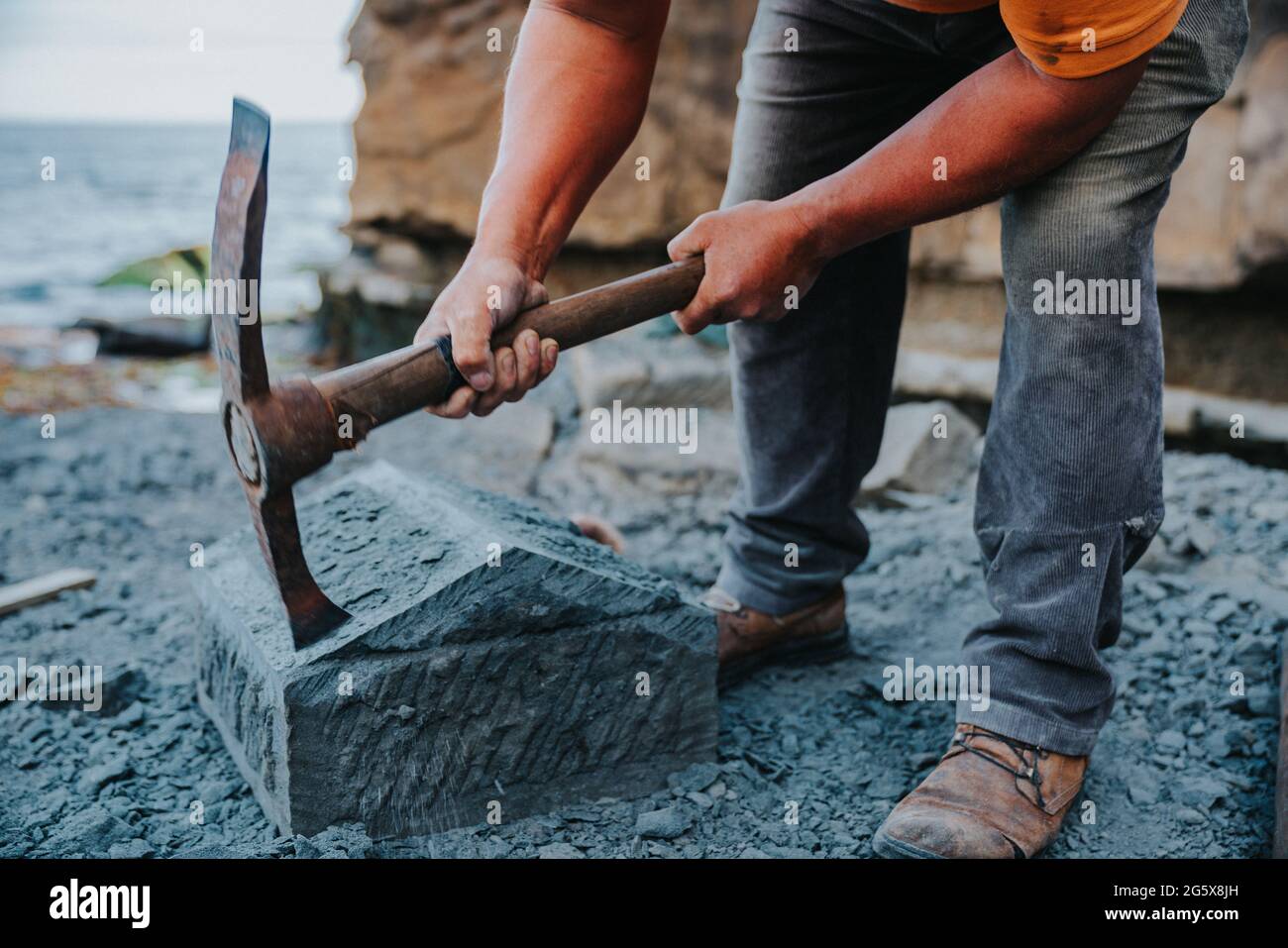 Un artisan en pierre qui coupe soigneusement un bloc de pierre d'anagua pour le façonner, dans la ville d'Ancud, île Chiloe. Banque D'Images