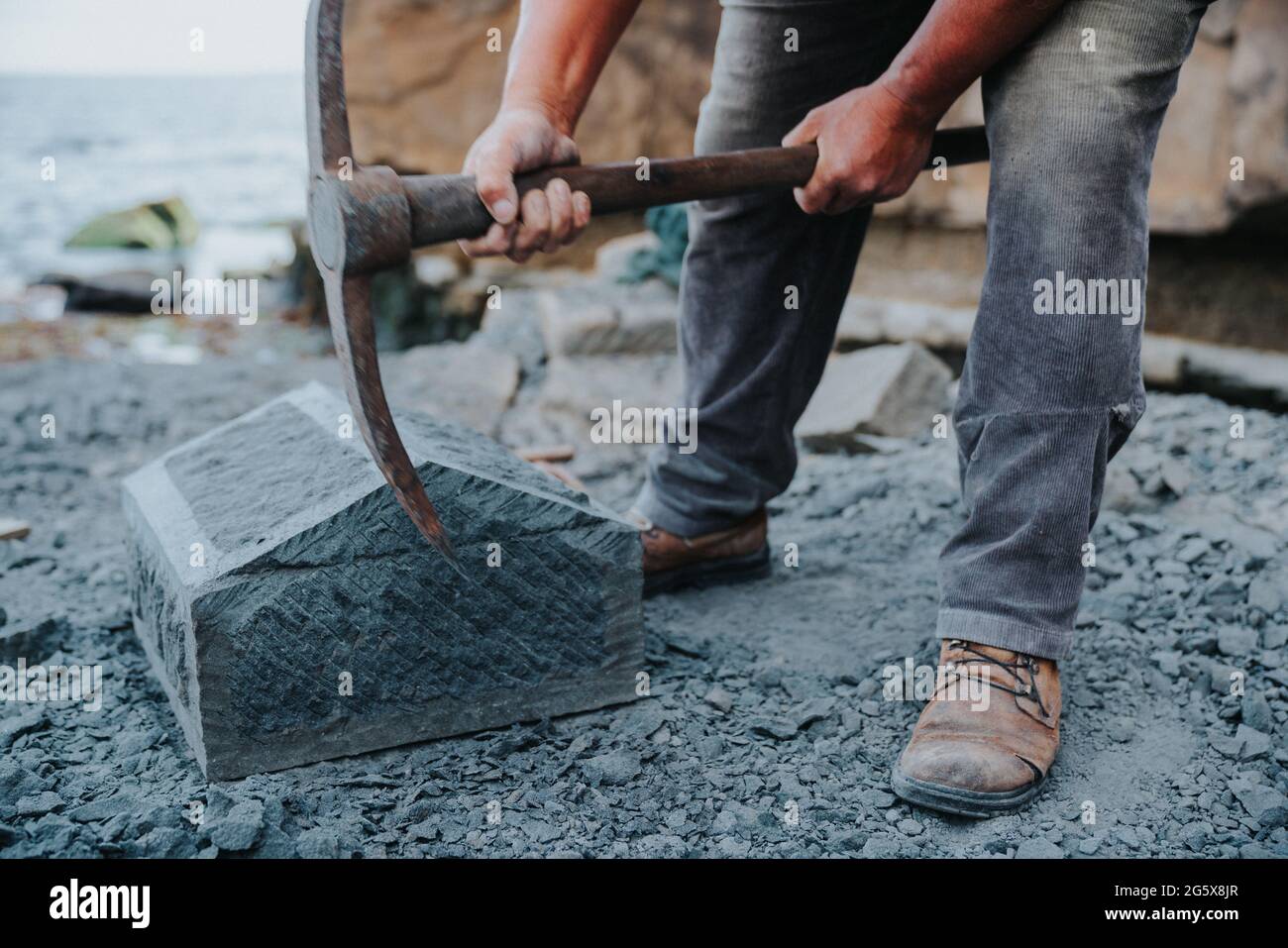 Un artisan en pierre qui coupe soigneusement un bloc de pierre d'anagua pour le façonner, dans la ville d'Ancud, île Chiloe. Banque D'Images