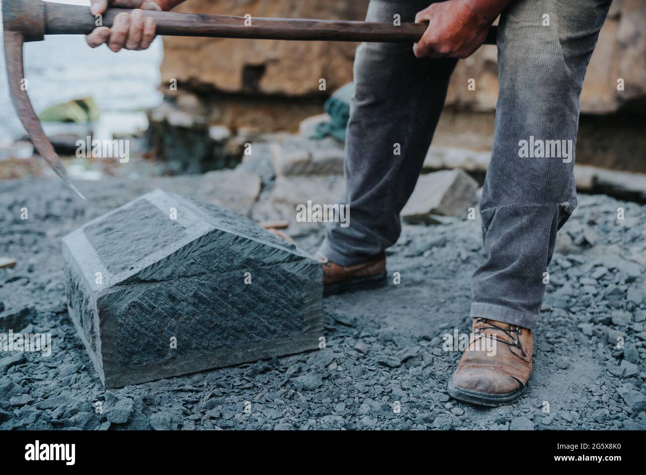 Un artisan en pierre qui coupe soigneusement un bloc de pierre d'anagua pour le façonner, dans la ville d'Ancud, île Chiloe. Banque D'Images