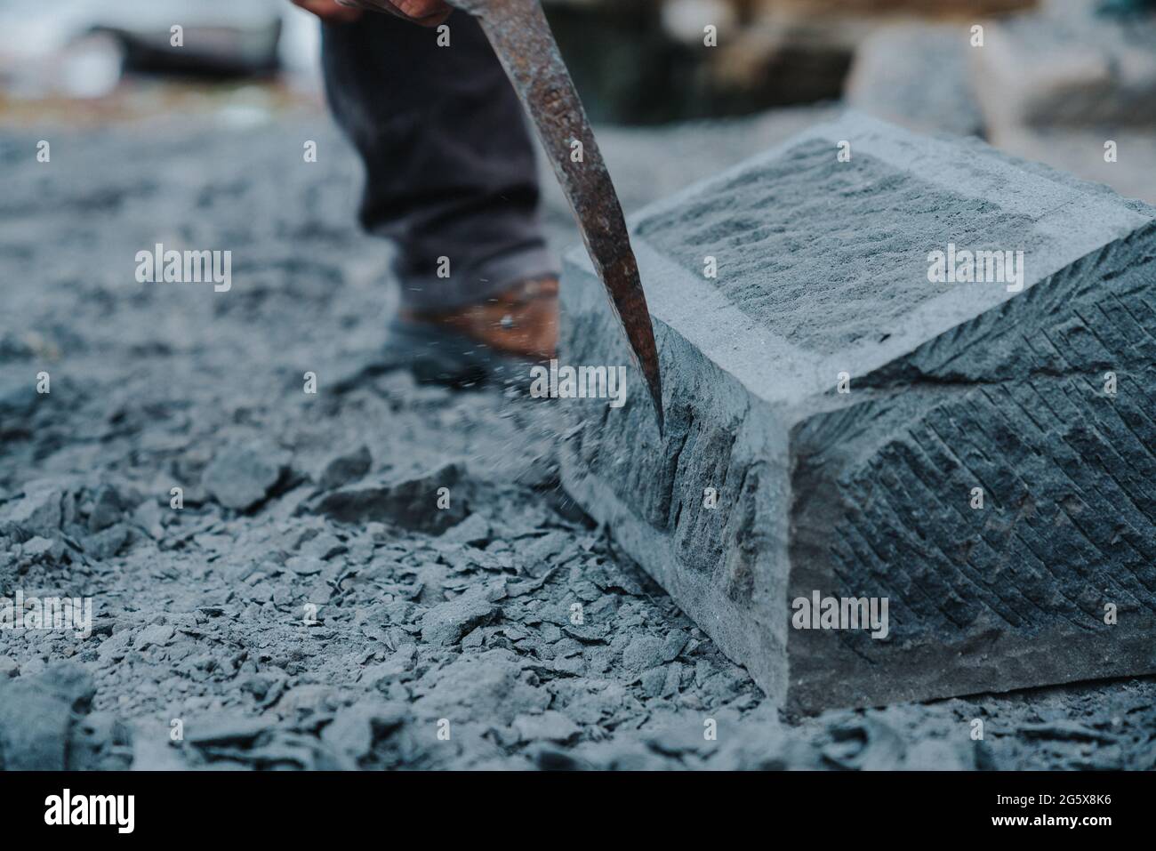 Un artisan en pierre qui coupe soigneusement un bloc de pierre d'anagua pour le façonner, dans la ville d'Ancud, île Chiloe. Banque D'Images