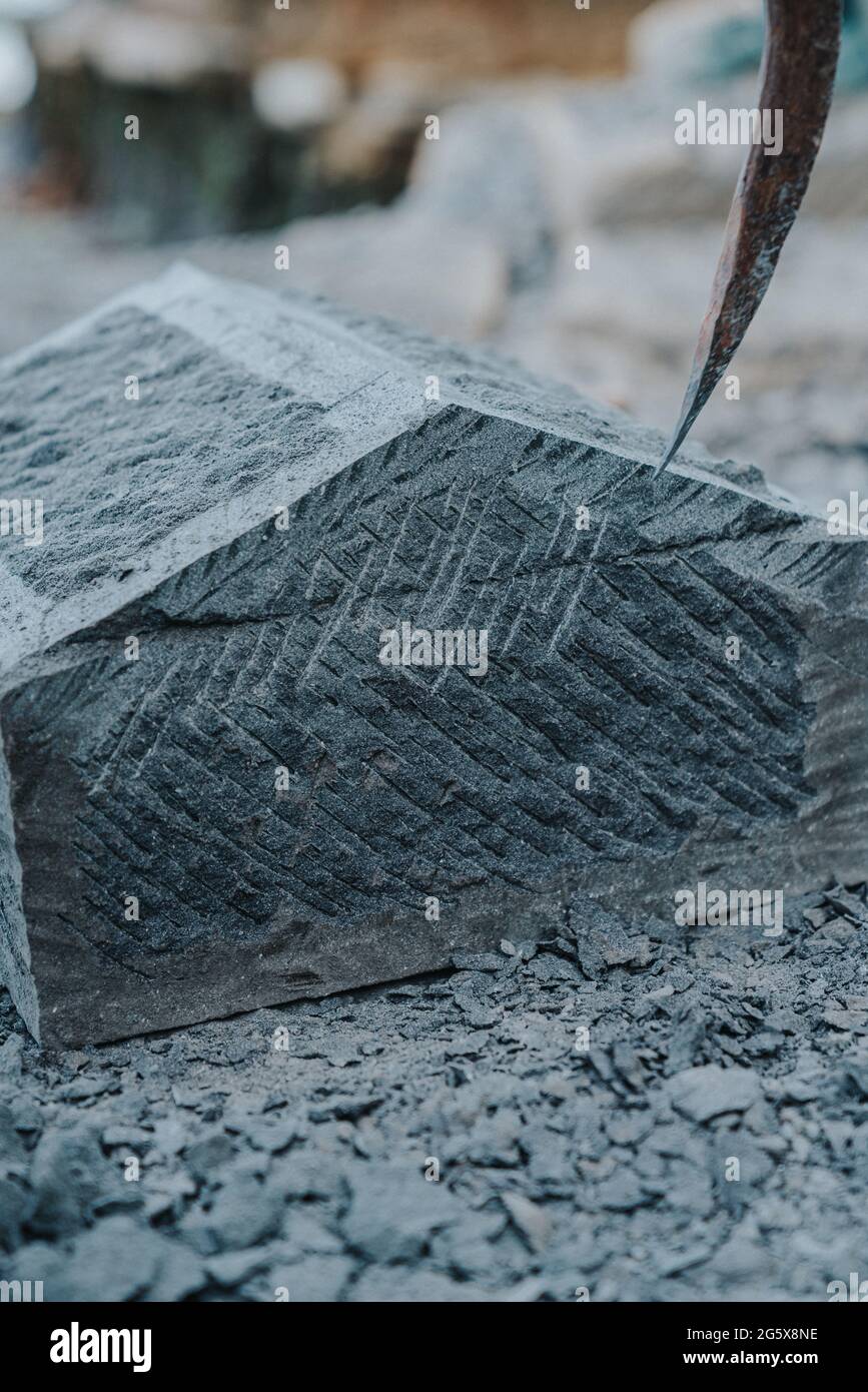 Un artisan en pierre qui coupe soigneusement un bloc de pierre d'anagua pour le façonner, dans la ville d'Ancud, île Chiloe. Banque D'Images