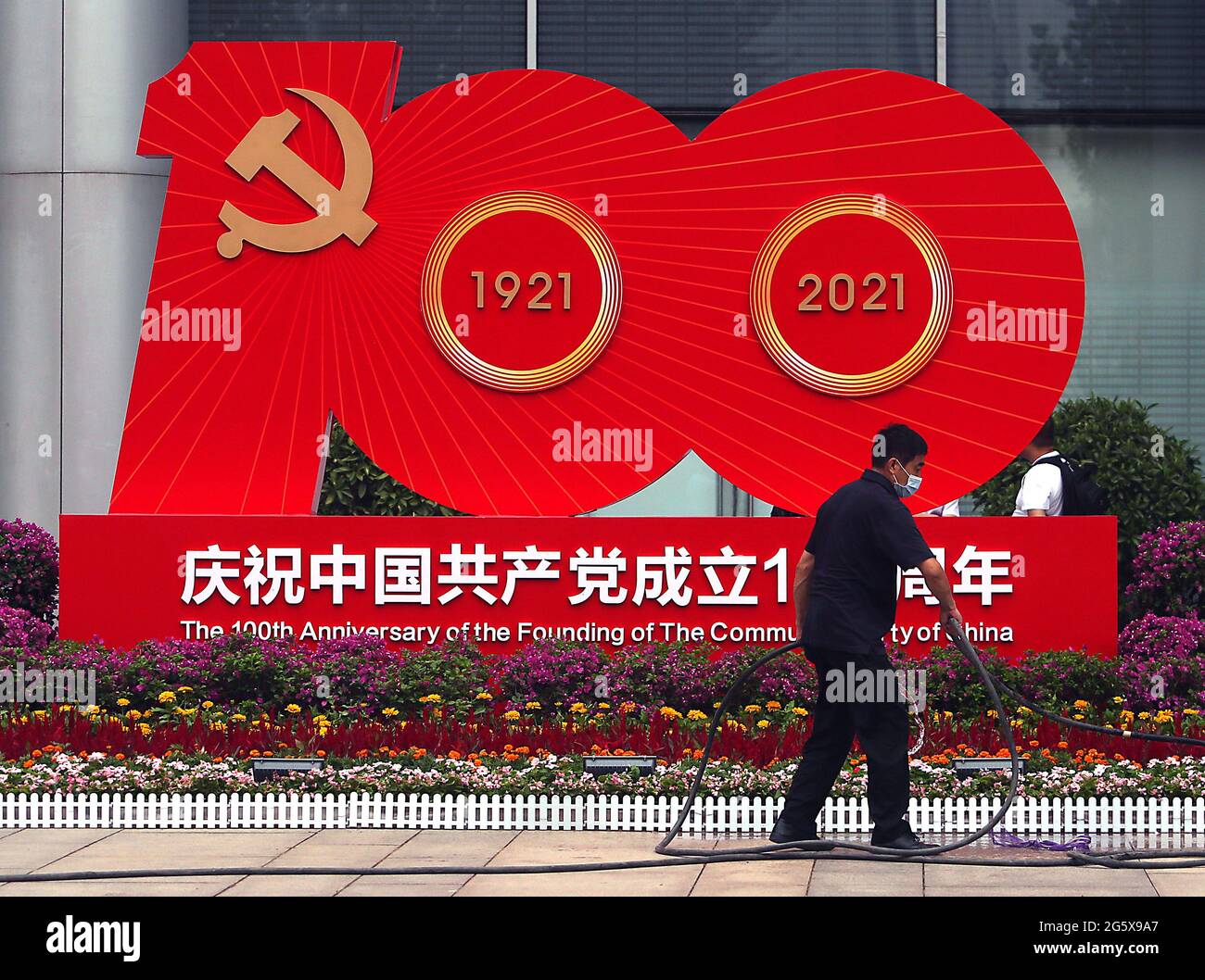 Pékin, Chine. 30 juin 2021. Un travailleur s'arrose près d'un panneau d'affichage commémorant le 100e anniversaire du Parti communiste chinois à Beijing, le mercredi 30 juin 2021. La Chine marque le centenaire de son Parti communiste au pouvoir cette semaine en annonçant ce qu'elle dit est son influence croissante à l'étranger, ainsi que son succès dans la lutte contre la corruption et la pauvreté dans son pays. Photo de Stephen Shaver/UPI crédit: UPI/Alay Live News Banque D'Images