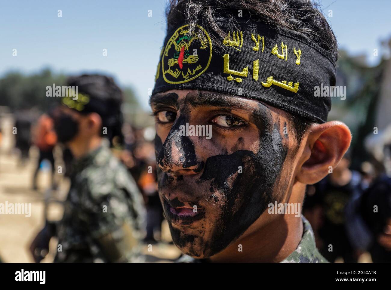 Un jeune palestinien portant le bandeau des Brigades d'Al Qods regarde  pendant une cérémonie de remise des diplômes dans un camp militaire d'été  organisé par le mouvement du Jihad islamique à Gaza