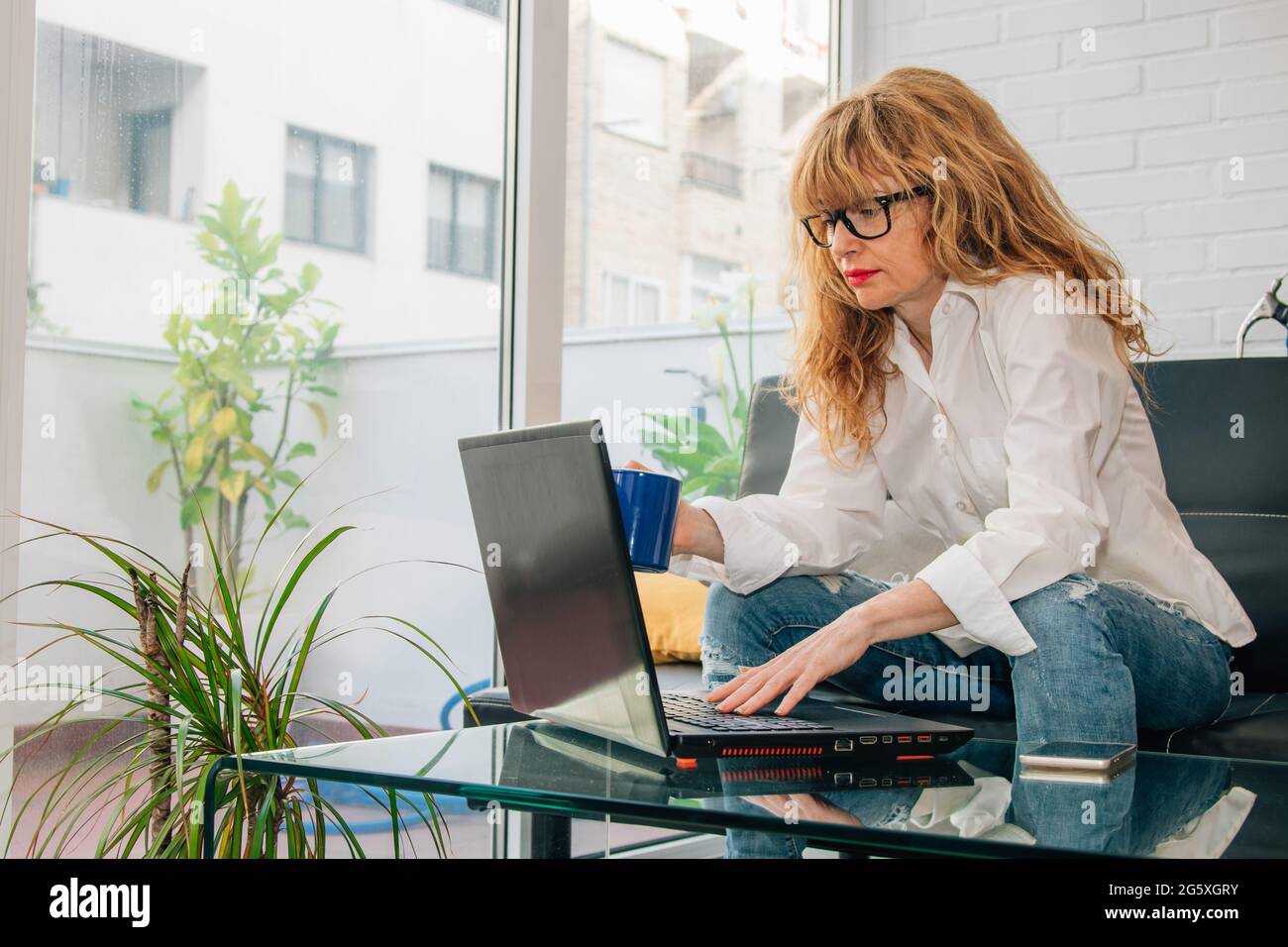 femme avec ordinateur et une tasse de café à la maison Banque D'Images