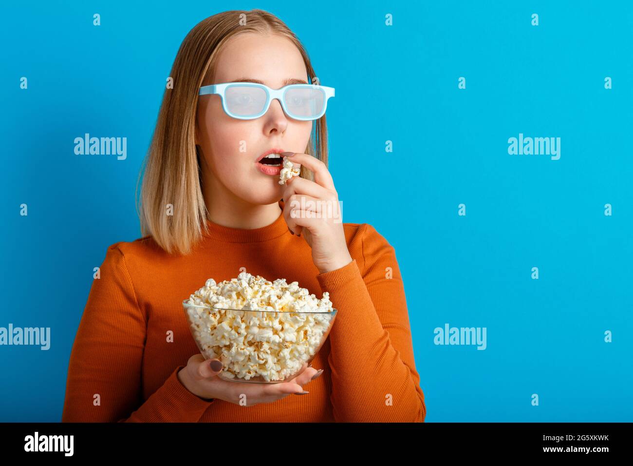 Portrait émotionnel de la jeune femme dans des lunettes de cinéma regardant un film 3d. Une jeune fille très enthousiaste qui regarde un film en lunettes mange du pop-corn avec un espace pour copier Banque D'Images