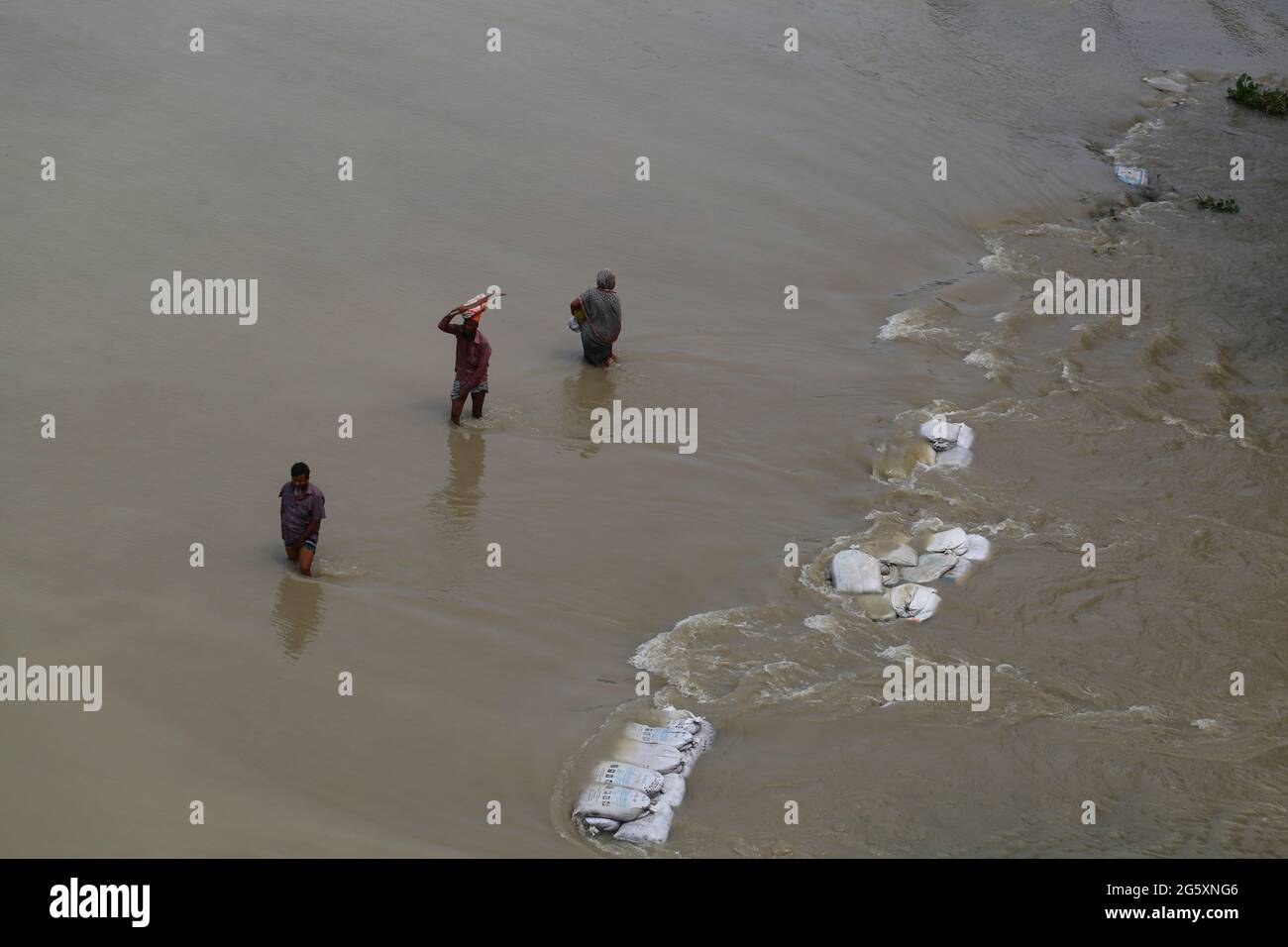 Les gens traversent les eaux de crue lors de l'inondation de la mousson à Munshiganj, près de Dhaka, au Bangladesh, le 28 juillet 2020. Plus de 9.6 millions de personnes ont été touchées par des inondations dues à la mousson, qui ont dévasté de vastes régions de l'Inde, du Bangladesh et du Népal. Banque D'Images
