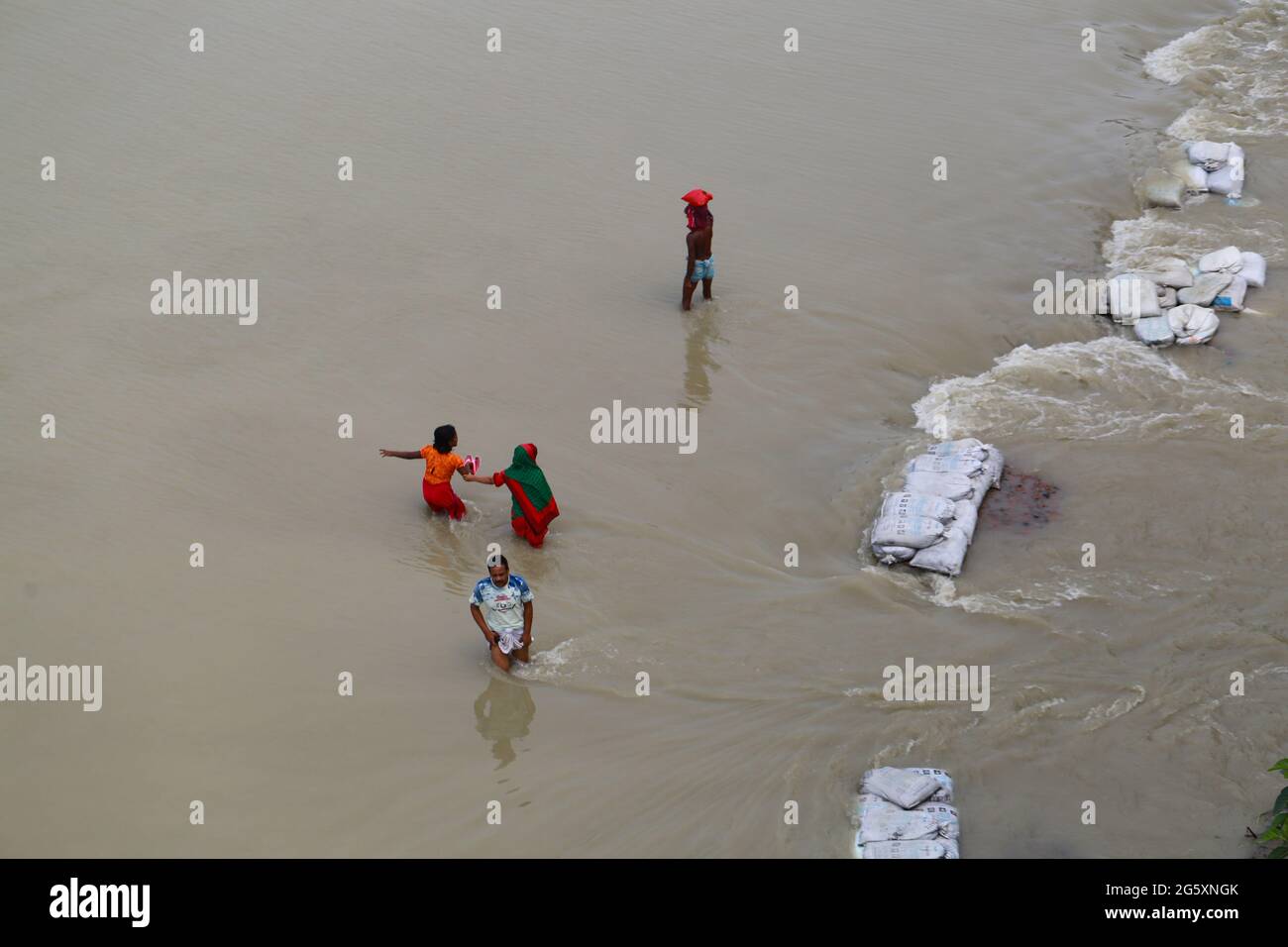Les gens traversent les eaux de crue lors de l'inondation de la mousson à Munshiganj, près de Dhaka, au Bangladesh, le 28 juillet 2020. Plus de 9.6 millions de personnes ont été touchées par des inondations dues à la mousson, qui ont dévasté de vastes régions de l'Inde, du Bangladesh et du Népal. Banque D'Images