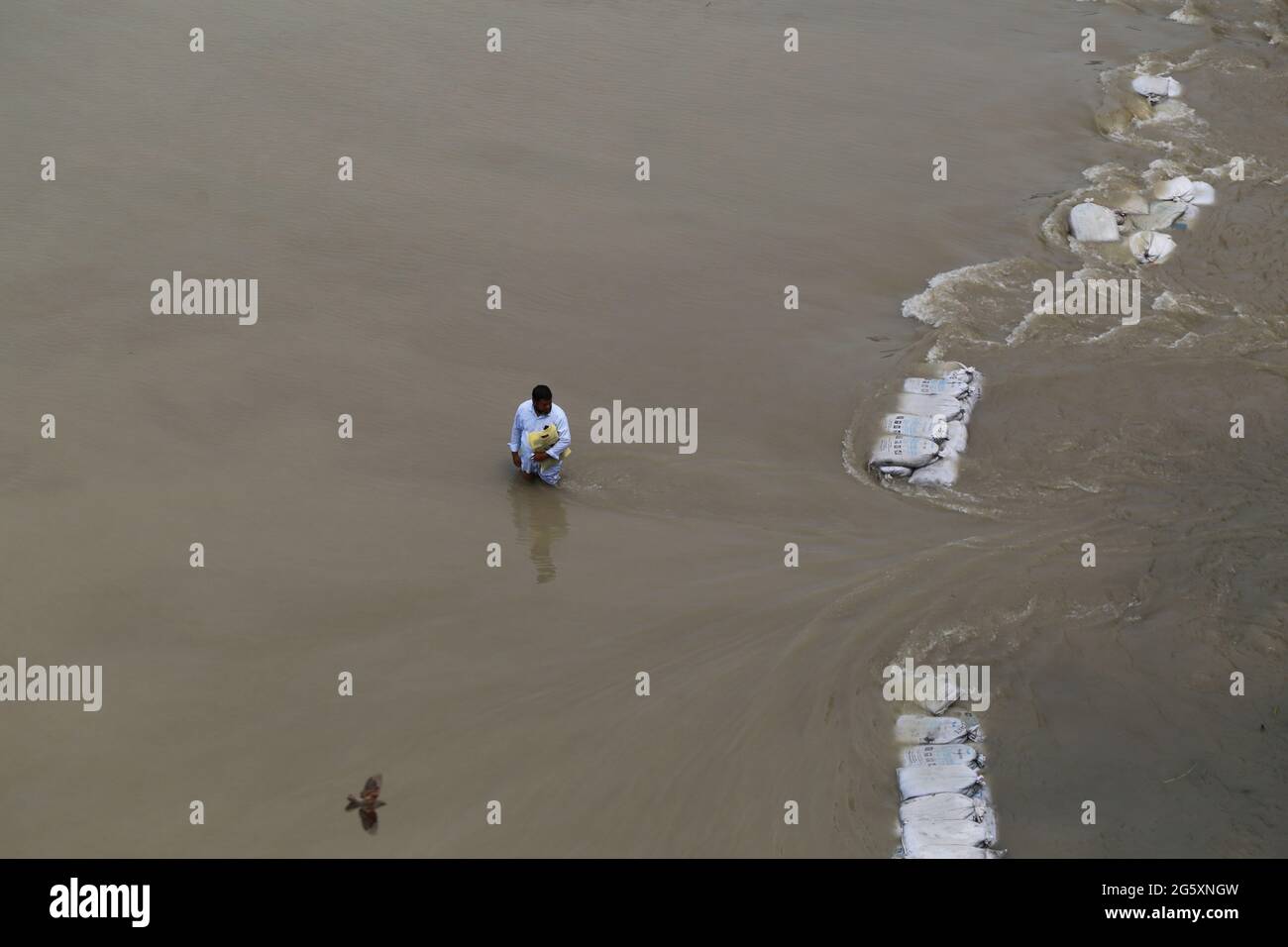 Un homme marche à travers les eaux de crue lors de l'inondation de la mousson à Munshiganj, près de Dhaka, au Bangladesh, le 28 juillet 2020. Plus de 9.6 millions de personnes ont été touchées par des inondations dues à la mousson, qui ont dévasté de vastes régions de l'Inde, du Bangladesh et du Népal. Banque D'Images