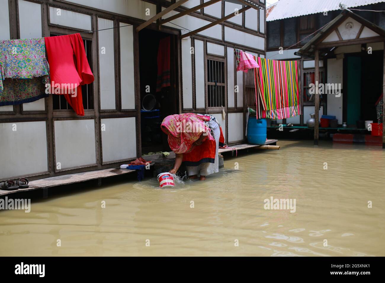 Le 28 juillet 2020, une femme lave un pot dans l'eau de crue lors de l'inondation de la mousson à Munshiganj, près de Dhaka, au Bangladesh. Plus de 9.6 millions de personnes ont été touchées par des inondations dues à la mousson, qui ont dévasté de vastes régions de l'Inde, du Bangladesh et du Népal. Banque D'Images