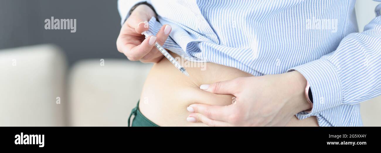 La femme s'injecte avec une aiguille et une seringue dans son estomac Banque D'Images