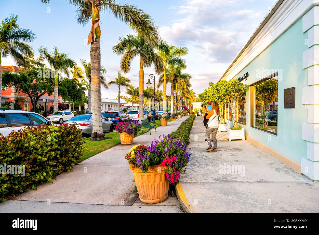 Naples, États-Unis - 29 avril 2018 : palmiers sur la rue dans le centre-ville de la plage de Floride au coucher du soleil et les gens sur les trottoirs pavés Banque D'Images