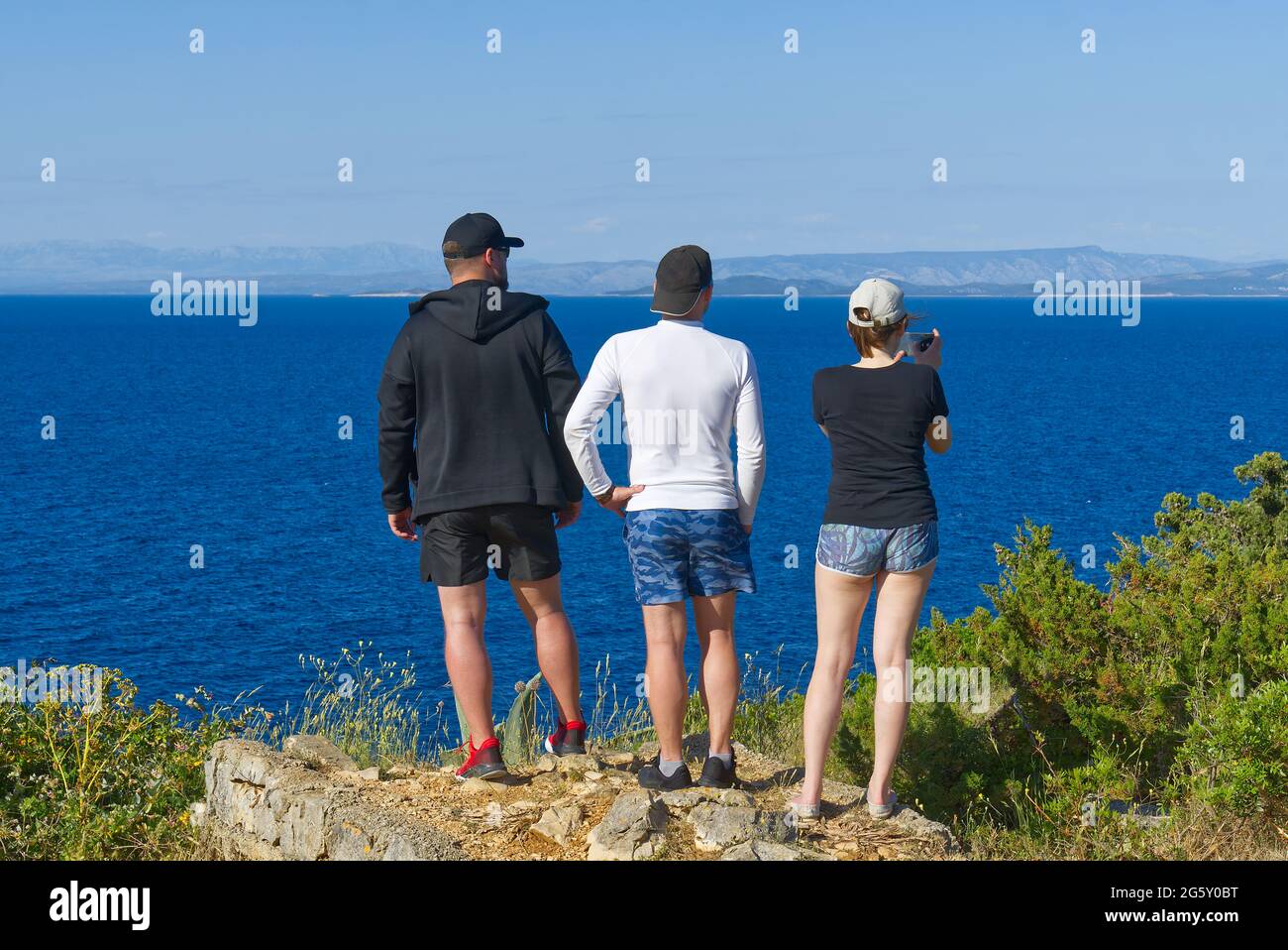 amis regardant sur une falaise au-dessus de la mer, randonneurs regardant la vue et appréciant la soirée d'été. activité Banque D'Images