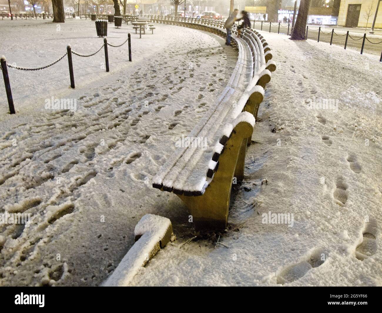Un couple monte sur un banc de parc enneigé. Banque D'Images