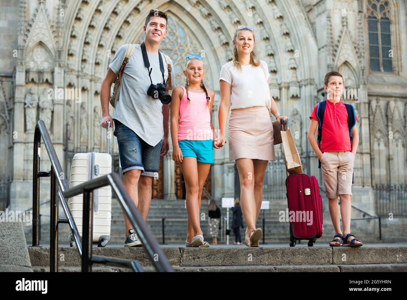 Famille de quatre personnes voyageant avec leurs bagages le long de la rue de la ville européenne Banque D'Images