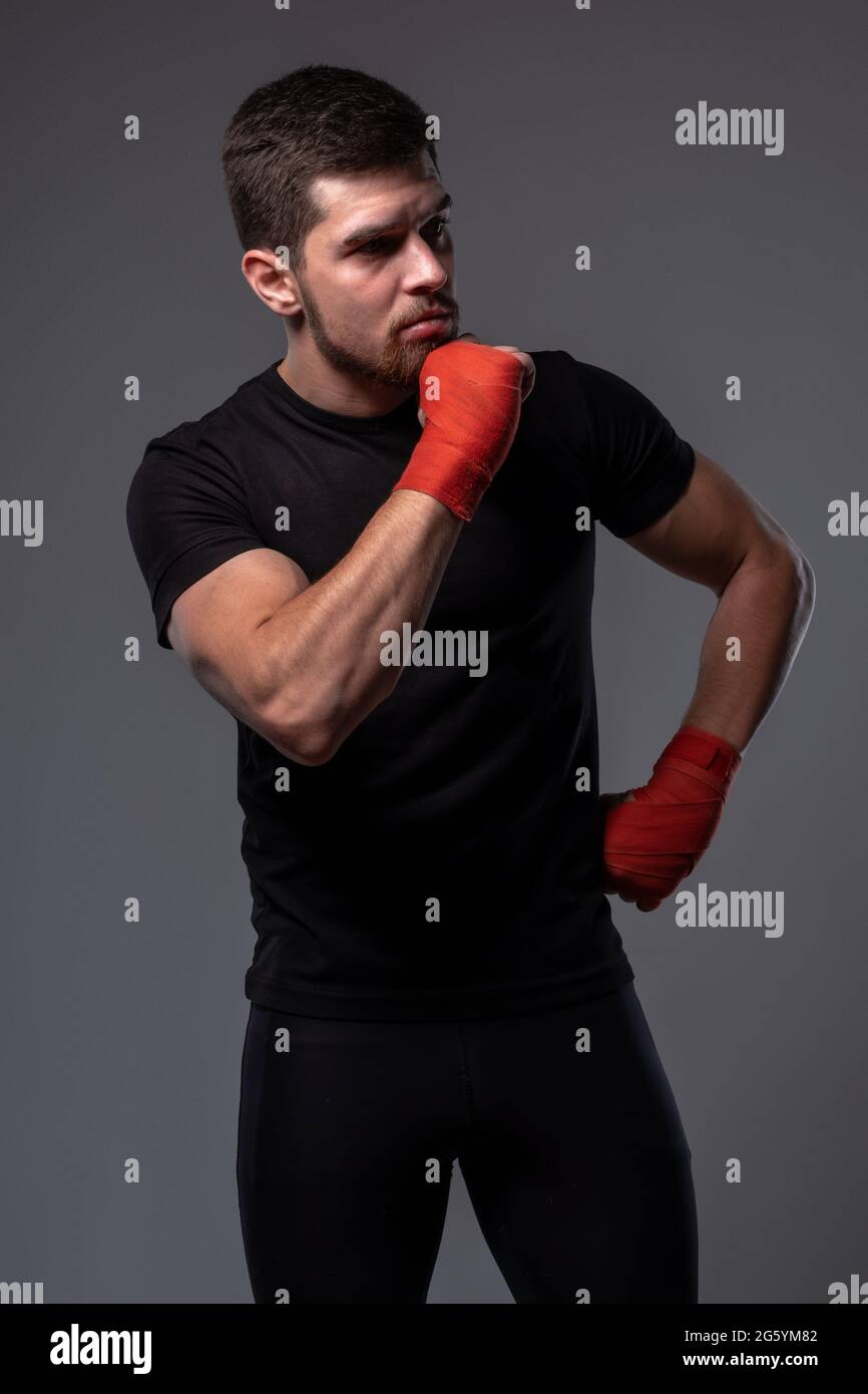 Homme sportif pensif avec bracelets de boxe sur fond gris Banque D'Images
