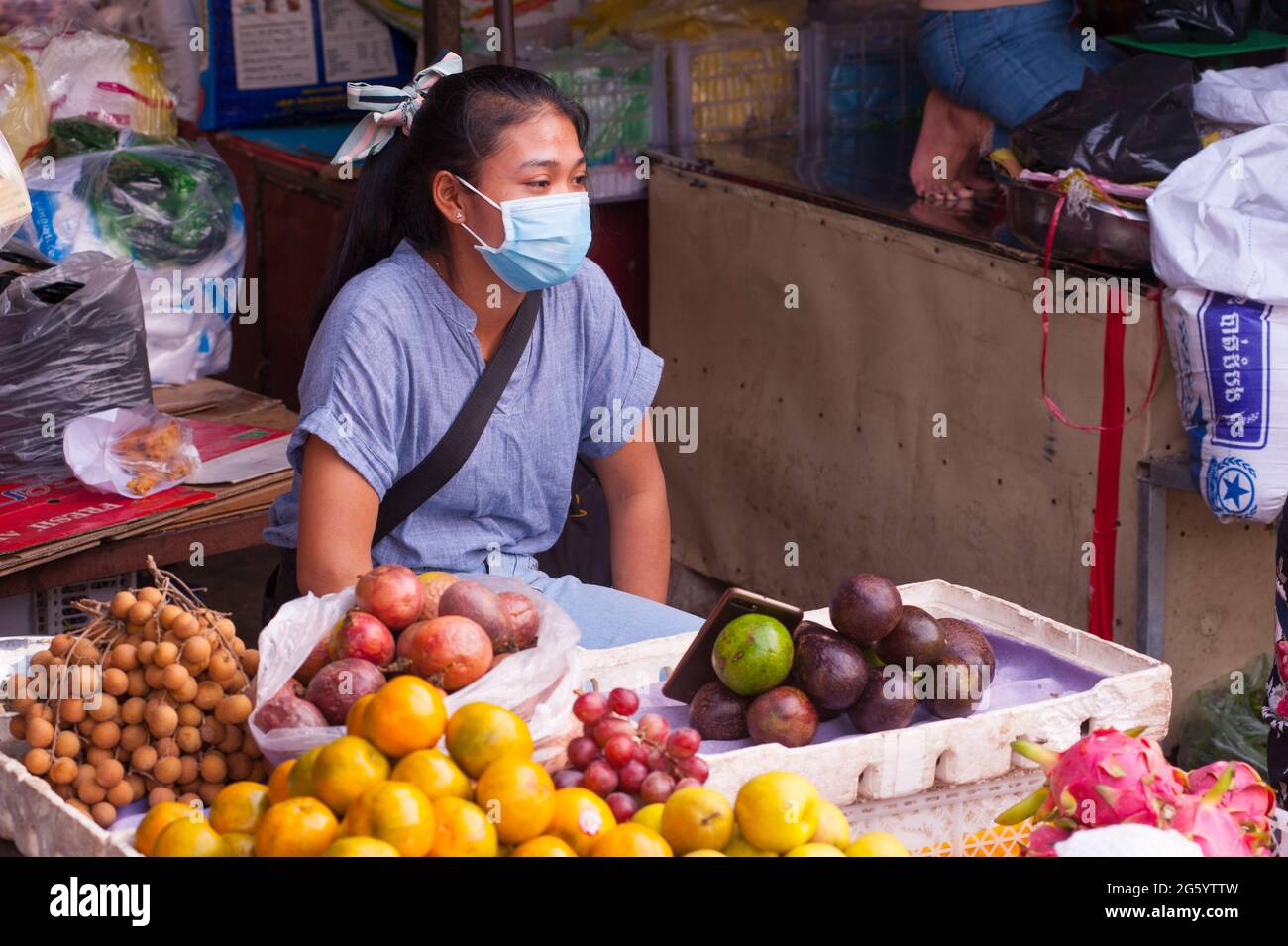 Vendeur de fruits frais tropicaux cambodgiens portant un masque de protection / couvrant au marché de Kandal pendant la pandémie du coronavirus. Phnom Penh, Cambodge. 18 mars 2020. © Kraig Lieb Banque D'Images