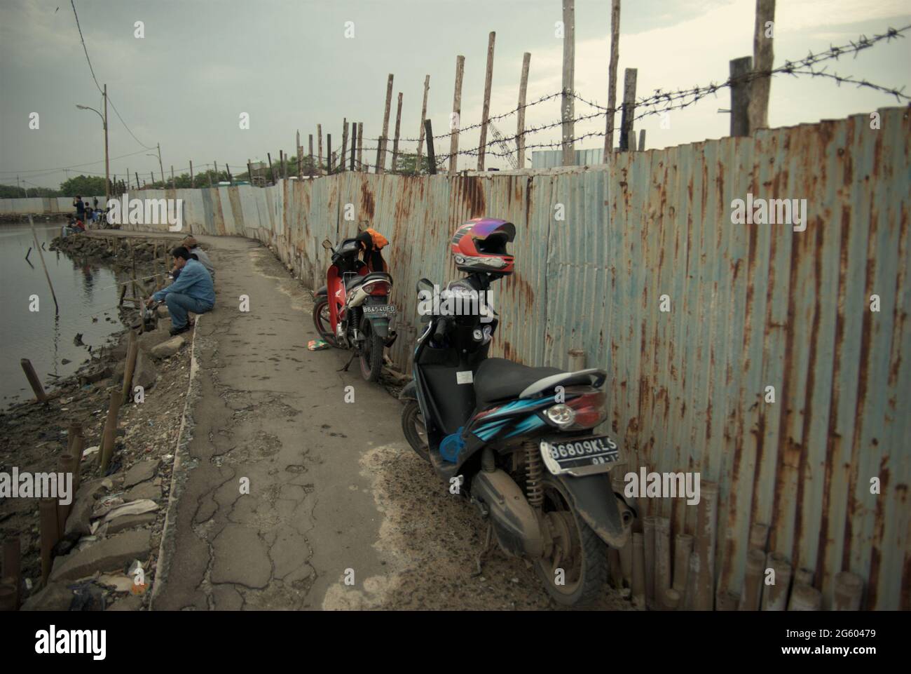 Une route étroite sur le côté de la clôture d'une zone de brise-navires près du village côtier de Marunda à Cilincing, Jakarta, Indonésie. Banque D'Images