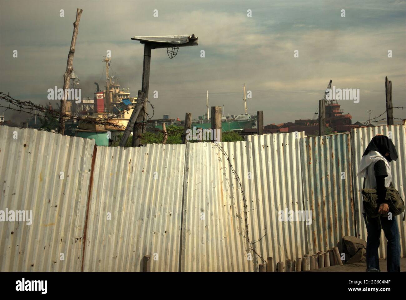 Une clôture qui sépare une route étroite avec une zone de chantier de démolition de navires, près du village côtier de Marunda à Cilincing, Jakarta, Indonésie. Banque D'Images