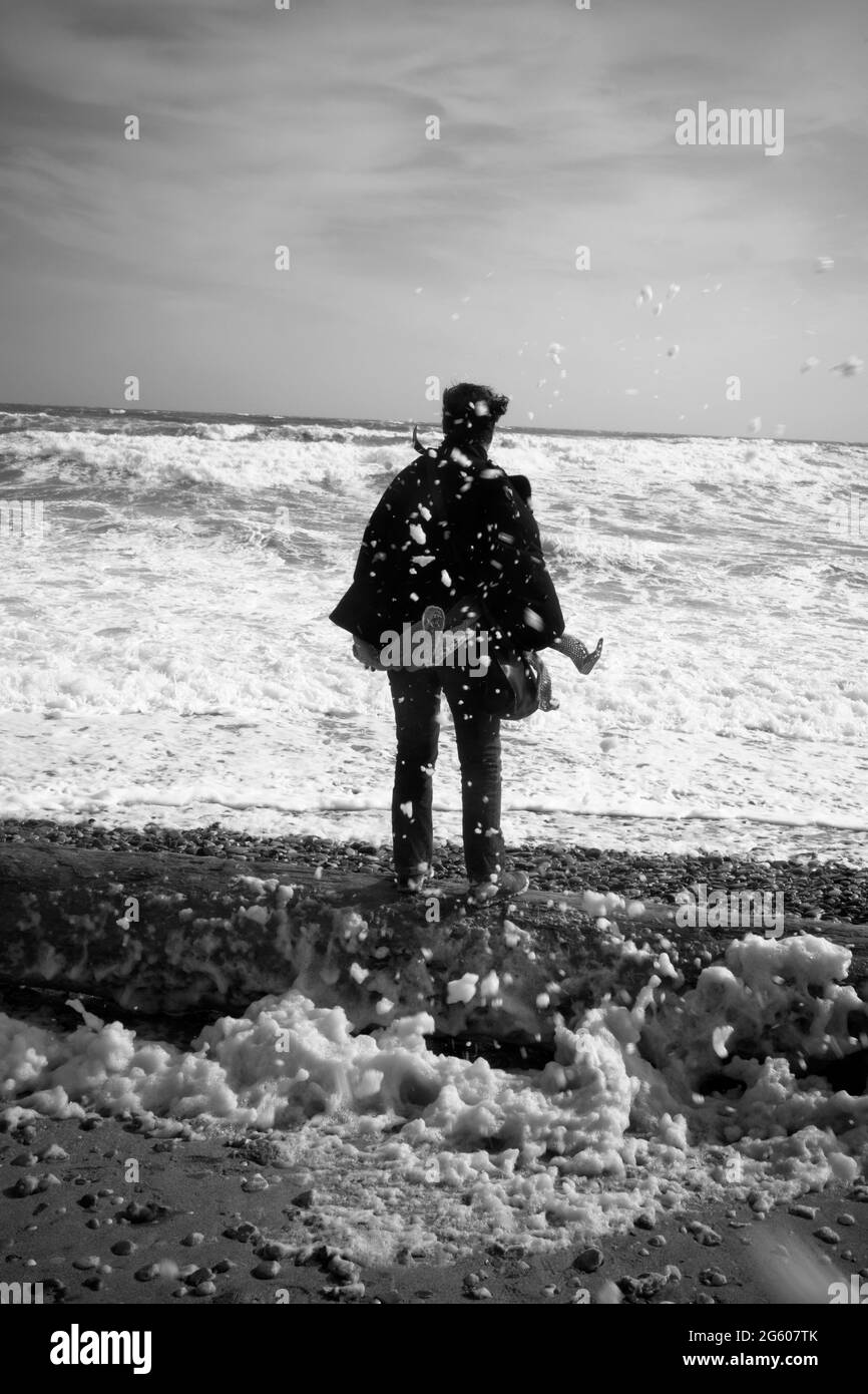 photo de la vue arrière des femmes qui se tiennent sur la plage et qui regardent la mer avec un jet qui survole autour d'elle par une journée venteuse et difficile dans le sud de la france Banque D'Images