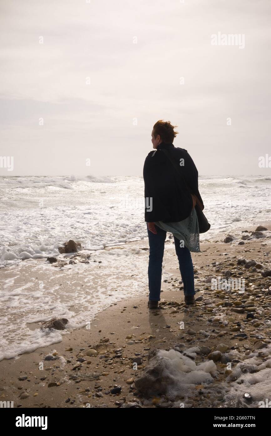 vue de profil des femmes se tenant sur la plage et regardant la mer avec jet volant autour d'elle lors d'une journée venteuse dans le sud de la france Banque D'Images